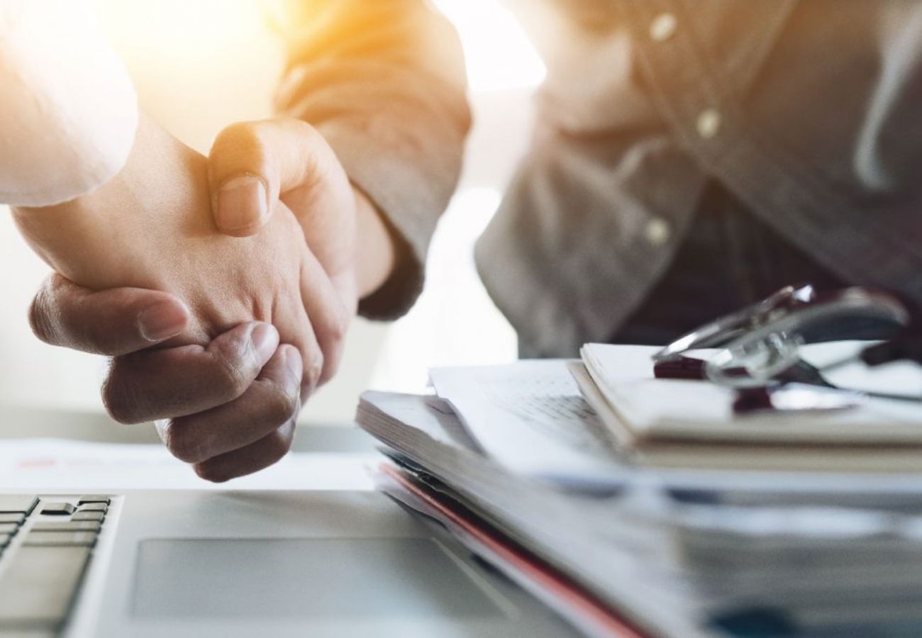 Mãos de um profissional assinando um contrato, representando negociação e fechamento de vendas.